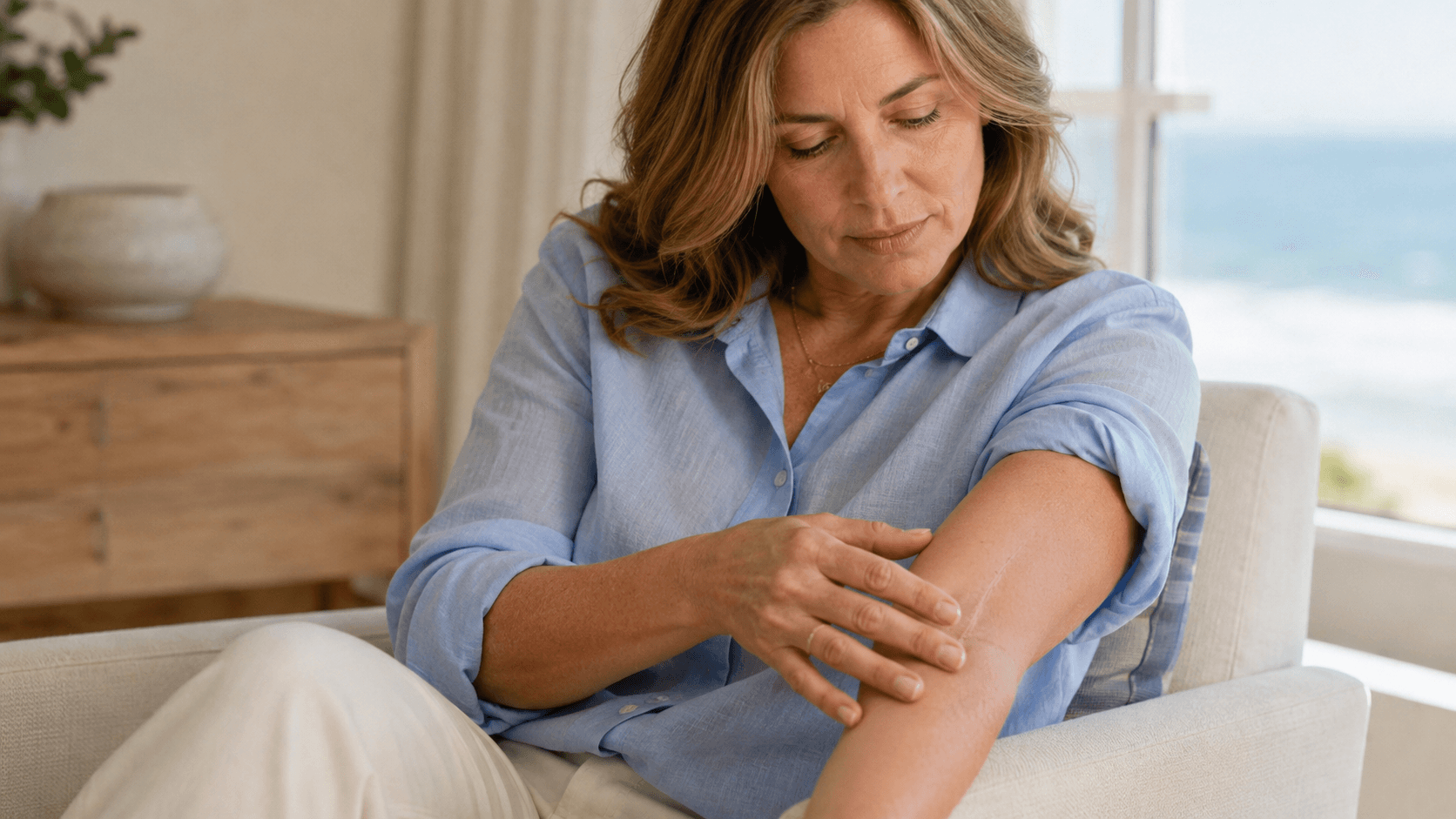 Adult gently examining a mature healed forearm scar in soft coastal light
